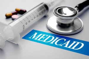 Medicaid, health concept. Stethoscope, syringe and pills on grey background